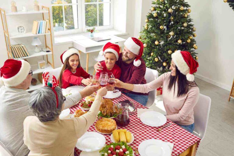 famiglia con cappelli di natale seduta a tavola che brina
