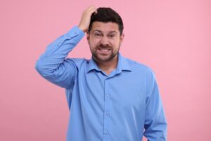 uomo imbarazzato che si gratta la testa con una mano