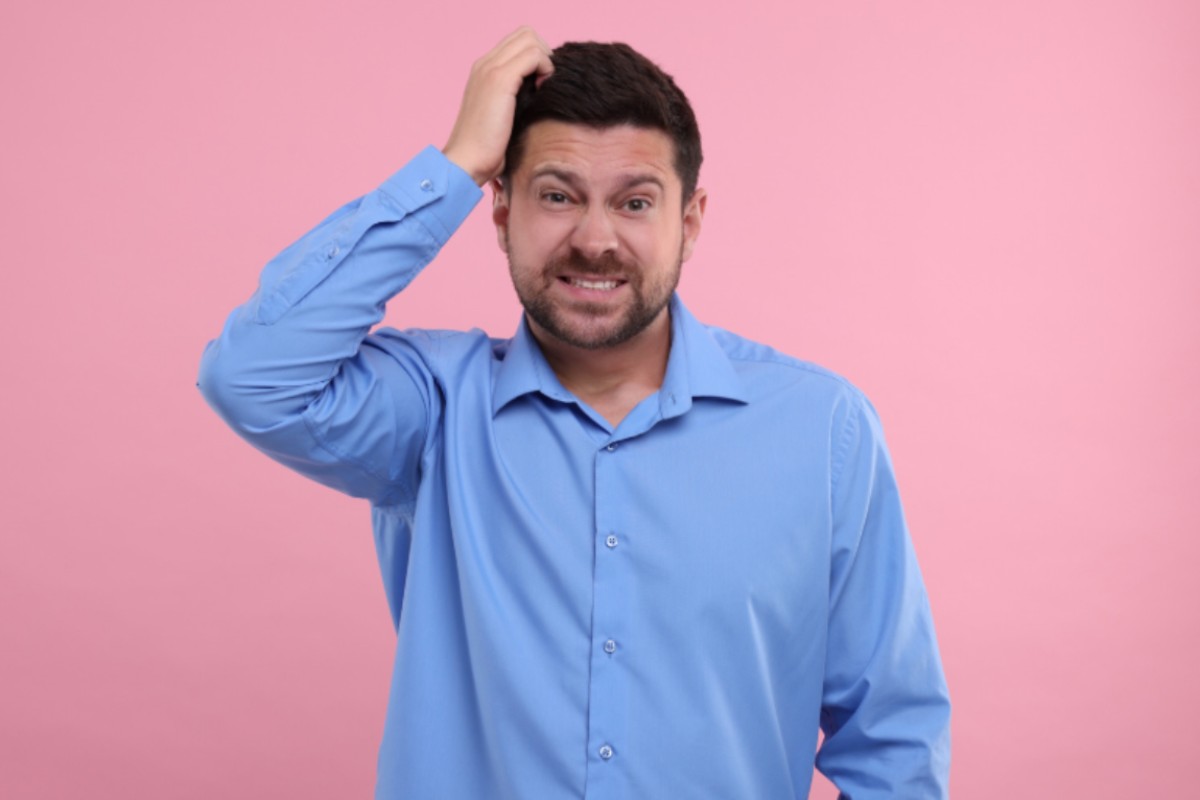 uomo imbarazzato che si gratta la testa con una mano