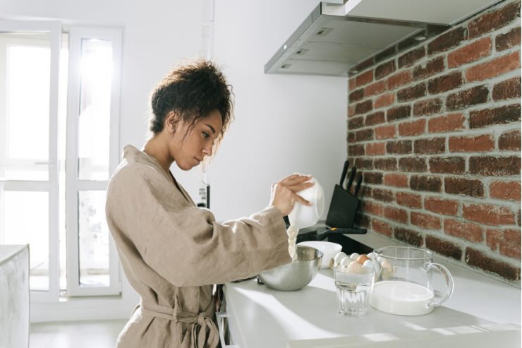 donna che cucina e diverse ciotole con ingredienti vari